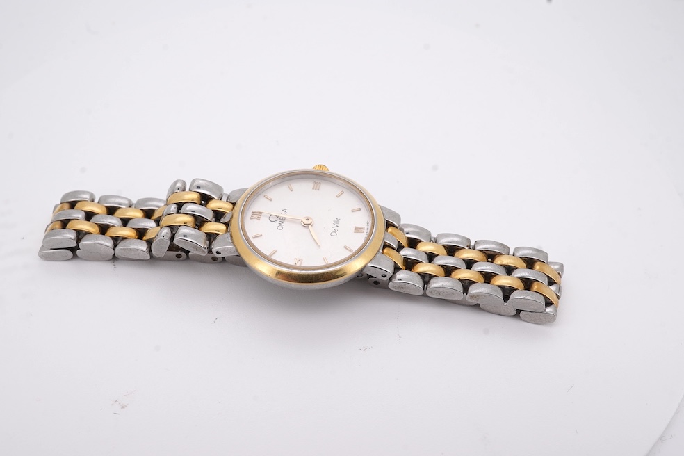A lady's steel and gold plated Omega de Ville quartz wrist watch, with baton and quarterly Roman numerals, on a stainless steel and gold plated bracelet, case diameter 24mm, no box or papers. Condition - poor to fair